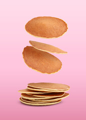 Many fresh pancakes falling on pink background