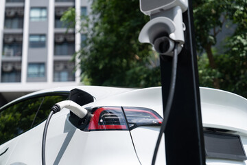 EV electric car charging in green sustainable city outdoor garden in summer. Urban sustainability...
