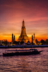 The famous Buddhist Temple Wat Arun during dusk with boat traffic on the Chao Phraya Rriver,...