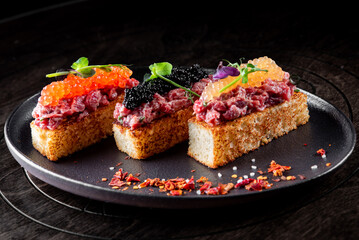 Canape with brioche, Raw beef meat tartar, salmon red caviar.