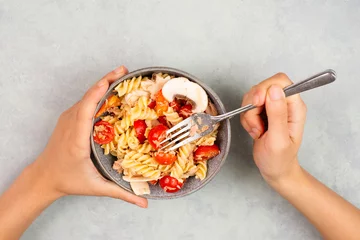 Poster Eating a pasta salad with sliced mushroom, tomato, red pepper pieces and tuna, healthy food with vegetables,  fresh organic nutrition  © Berit Kessler