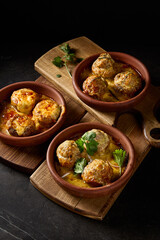 Vertical side view showcasing baked mushrooms stuffed with suluguni cheese and meat, elegantly presented on rustic wooden planks, set against a stark black background