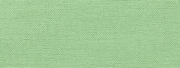 Texture of light green color background from textile material with wicker pattern, macro. Vintage olive fabric cloth