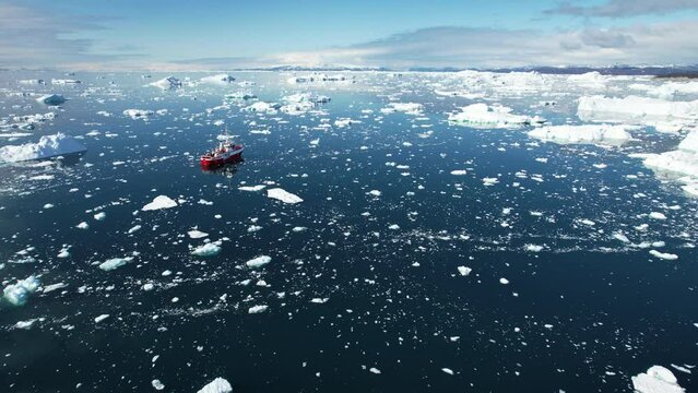 Scientist ship in ocean with flowing iceberg in Greenland, aerial view