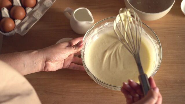 Woman prepares dough for pancakes. Mixing baking ingredients. Cooking, preparing breakfast, dessert