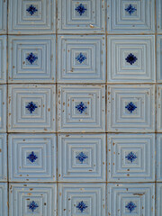 Part of a typical Portuguese wall decorated with tiles. Nice shades of blue. Worn tiles. Portugal. Vertical photo.