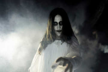 Portrait of spooky female ghost in smoke at night