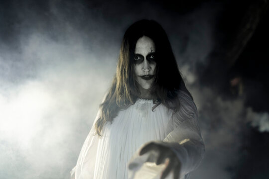 Portrait of spooky female ghost in smoke at night