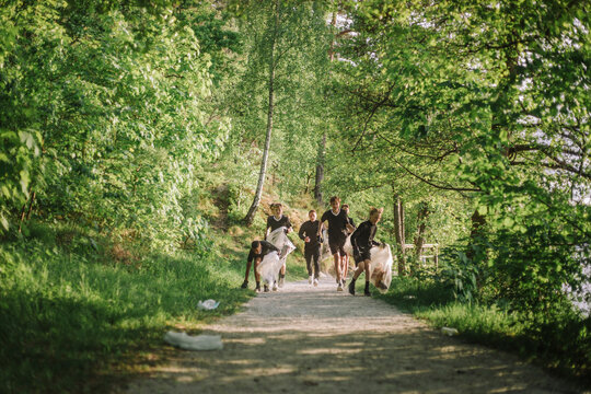 Boys and coach plogging on footpath amidst green plants