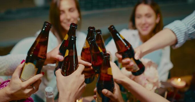 Group of friends drinking beer in backyard party and clinking bottles, closeup, 4K, Prores