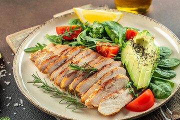 Fresh green salad with grilled chicken fillet, tomatoes, avocado, lemon on light background. Diet Concept. Top view copy space