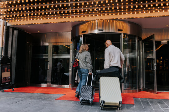 Senior man and woman puling luggage while entering in movie theater