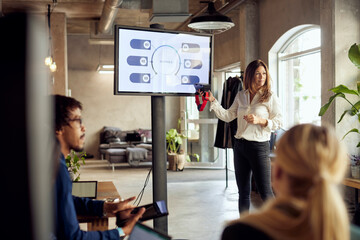 Confident businesswoman holding VR simulator while explaining during meeting