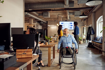 Smiling businessman with disability on wheelchair at creative office