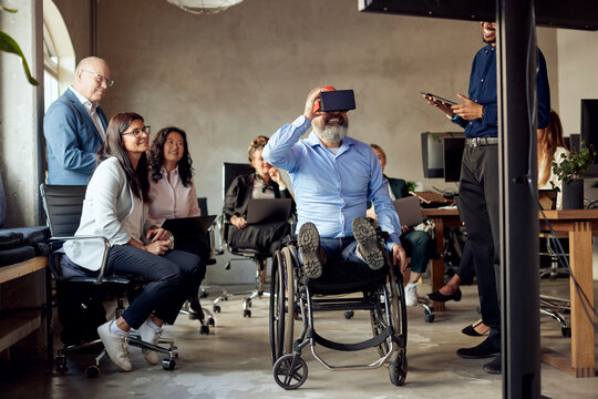 Businessman with disability wearing VR simulator amidst colleagues at creative office