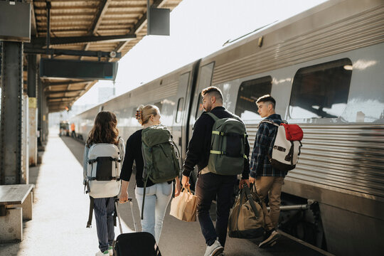 Family talking to each other while walking with luggage near train at railroad station