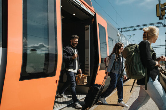 Smiling man with family disembarking from train at station