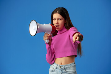 Teen girl making announcement with megaphone on blue background