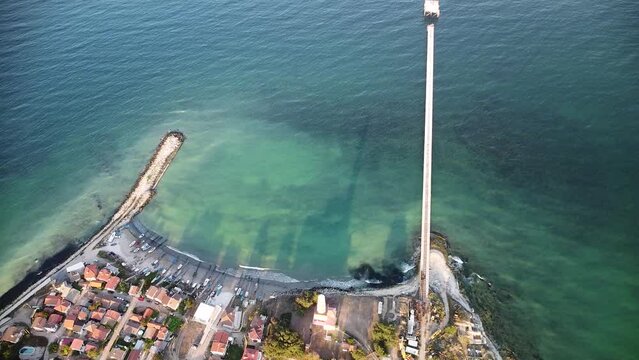 Aerial drone footage of the Shabla lighthouse, beach and surf. Top down high angle shot of green sea and red white vintage lighthouse at the coast of Bulgaria.

