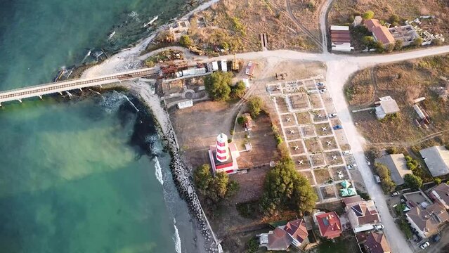 Aerial drone footage of the Shabla lighthouse, beach and surf. Top down high angle shot of green sea and red white vintage lighthouse at the coast of Bulgaria.
