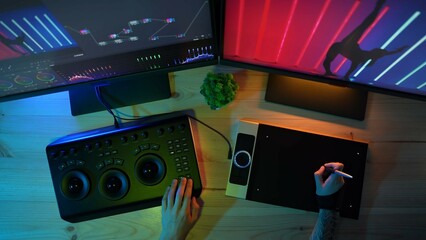 Top view of monitors and male hands working at the desk at home, editing photo using graphic tablet.