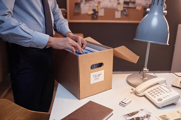 Close up of male detective looking through files on desk while standing in office, copy space