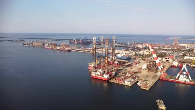 Aerial drone footage of a Jackup drill rig docked for maintenance and repairs. Oil discovery platform at a port filmed from above.
