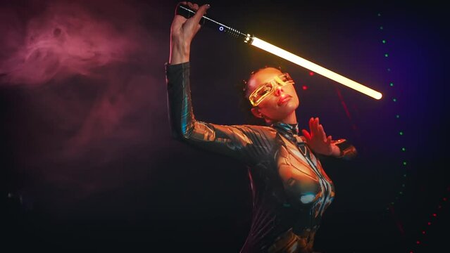 Fantasy cyborg woman creative robot costume glowing glasses metal body cyberpunk style braid hairstyle. Sexy alien girl in virtual reality game lady warrior future holding vr laser sword in hands. 4k