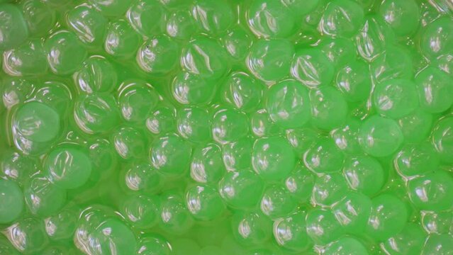 Apple bobas for bubble tea made with agar agar and fruit juice in a container. Slow motion overhead view.