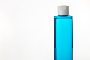 Makeup remover in plastic blue bottle isolated on white background. Natural organic beauty liquid product. Micellar water for cleansing and moisturizing facial skin..