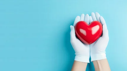 Fotobehang Heart disease prevention - medical gloves holding heart model on light blue background © hassan