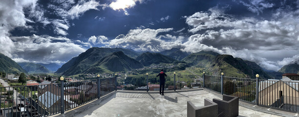 Mann (von hinten) steht am Geländer der Dachterasse eines Hotels in Stepanzminda und blickt zur Gergetier Dreifaltigkeitskirche, Kaukasus, Kasbek, Mzcheta-Mtianeti, Georgien