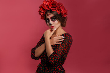 Portrait of scary woman with halloween makeup. Pretty female model posing in mexican attire in day of the dead.