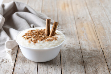 Arroz con leche. Rice pudding with cinnamon in bowl on wooden table. Copy space