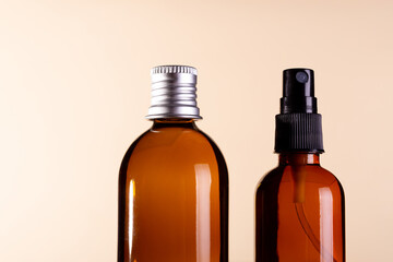 Amber glass cosmetic packaging with blank labels on beige background. Flat lay, top view pump bottle with soap and sprayer. SPA natural organic cosmetics. close up.