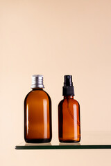 Two cosmetics dark amber glass bottles on beige background. Closeup, copyspace. Beauty blog, salon treatment concept, minimalism brand packaging mock up.