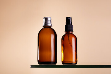 Two cosmetics dark amber glass bottles on beige background. Closeup, copyspace. Beauty blog, salon treatment concept, minimalism brand packaging mock up.