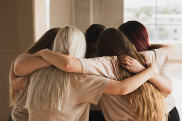 team of girls standing round and hug each other, team spirit and motivation