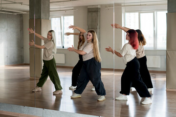 team of young female dancers practice choreography in the studio in front of the mirror