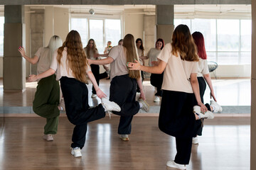 team of young female dancers practice choreography in the studio in front of the mirror