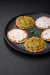 Round snacks with crispy chips or crackers with cream cheese and pesto