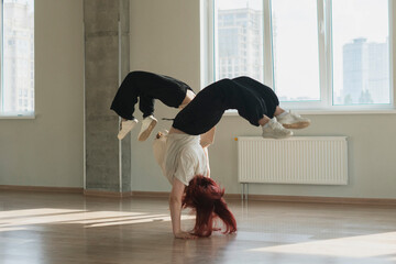 two girls doing synchrone acrobatic moves in the dance studio