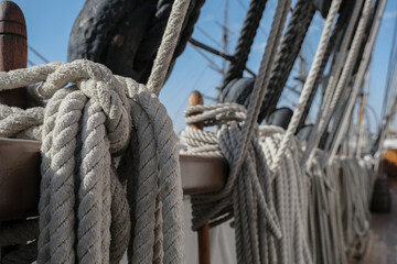 Ropes, rigging and tackles, hawsers on outdoor wooden deck of windjammer sailing boat yacht with sails, masts and ship superstructure