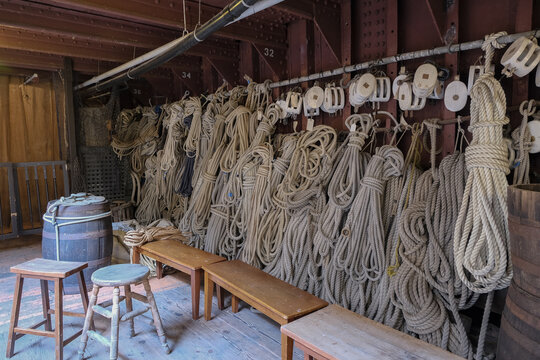 Ropes, rigging and tackles, hawsers on outdoor wooden deck of windjammer sailing boat yacht with sails, masts and ship superstructure