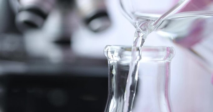 Scientist chemist pouring water from test tube into flask in laboratory closeup 4k movie slow motion. Tap water quality control concept