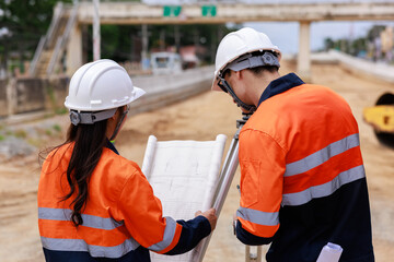 Engineer use theodolite equipment and looking blueprints construction project for route surveying...