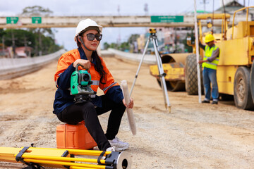 Portrait of Engineer sitting and holding theodolite equipment in construction site,