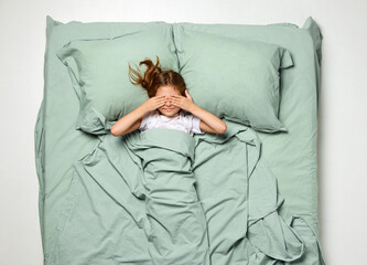 Top view. Little beautiful girl covered eyes with hands to wake up feel. Happy cheerful kid, child...