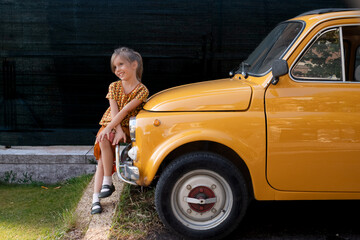 young smiling child leaning a fiat 500 classic car