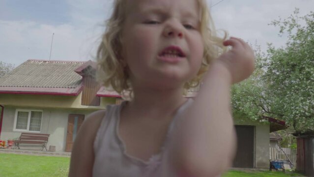 a little girl is talking to the camera,waving hands and pointing and talking close-up to the camera, shooting yourself on camera